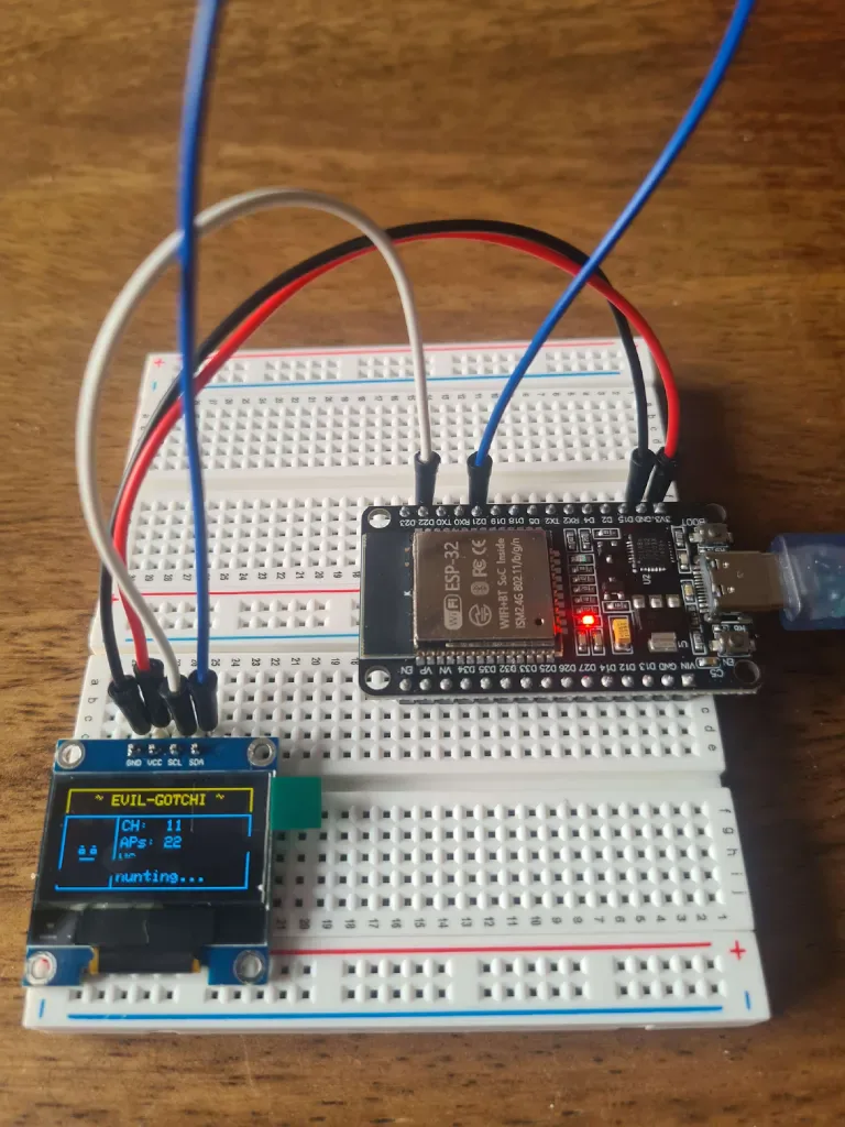 EVIL-GOTCHI prototype on a breadboard with an ESP32 wired to a small OLED showing its hunting screen